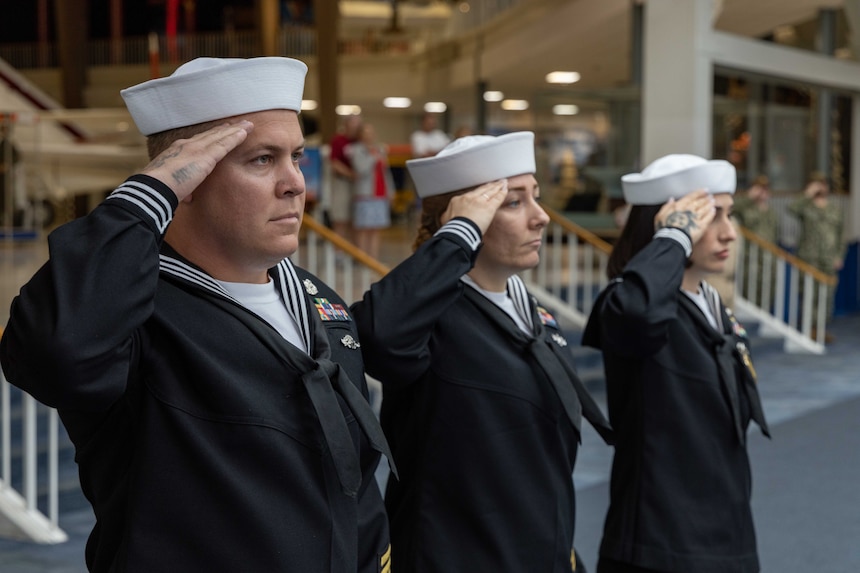 Navy Diver 1st Class Chase S. McCain, left, assigned to Naval Diving and Salvage Training Center Panama City, salutes during the national anthem during Naval Education and Training Command’s (NETC) fiscal year 2022 Sailor of the Year (SOY) announcement and award ceremony at the National Naval Aviation Museum in Pensacola, Florida, May 11, 2023. NETC's mission is to recruit, train and deliver those who serve our nation, taking them from street-to-fleet by forging civilians into highly skilled, operational and combat ready warfighters. (United States Navy photo by Mass Communication Specialist 2nd Class Zachary Melvin)