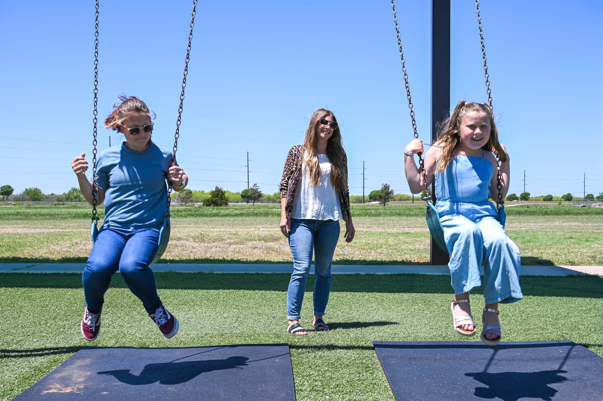 Trisha Fleishman, 97th Civil Engineering Squadron water quality program manager, pushes her daughters, Layla (left) and Margie (right), on a swing set at Altus Air Force Base, Oklahoma, May 4, 2023. Women make up 28.7% of the civilian workforce in the U.S. Air Force. (U.S. Air Force photo by Senior Airman Kayla Christenson)