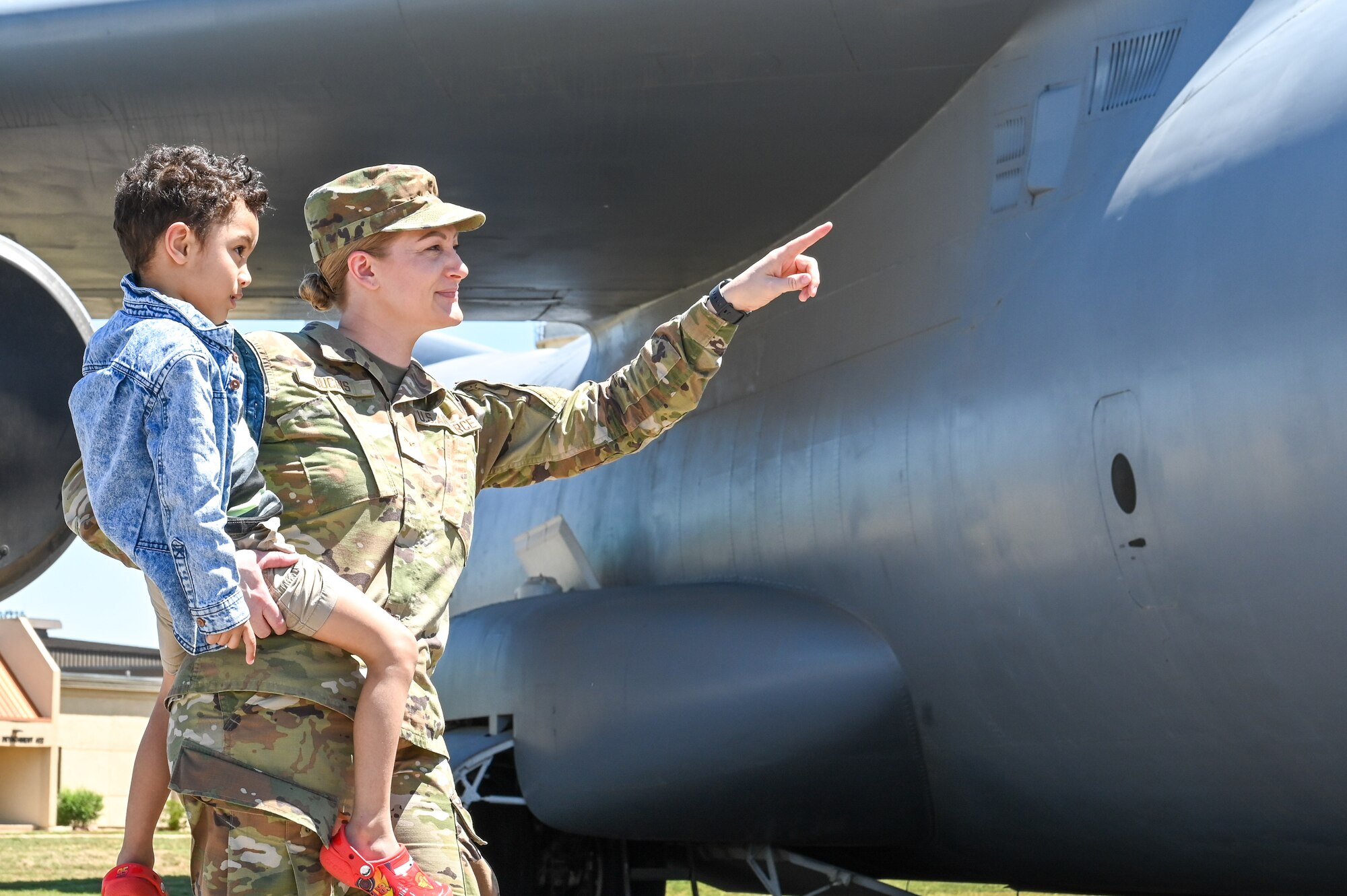 U.S. Air Force Airman 1st Class Heidi Bucins, 97th Air Mobility Wing public affairs apprentice, points to a static display with her son, Noah, at Altus Air Force Base, Oklahoma, May 4, 2023. Women make up 20.9% of the U.S. Air Force enlisted corps. (U.S. Air Force photo by Senior Airman Kayla Christenson)