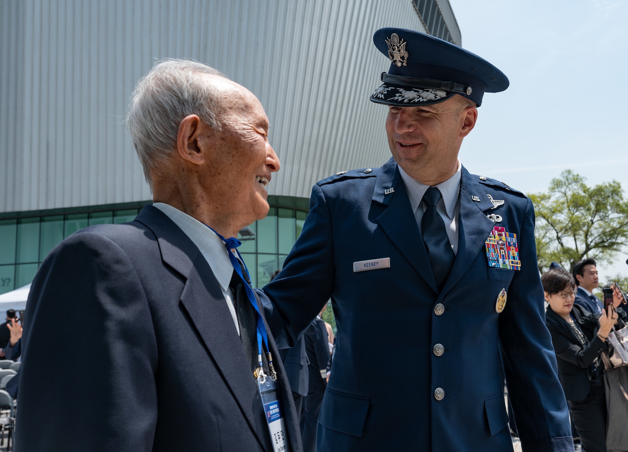 Mr. Kim, left, former Republic of Korea pilot, and U.S. Air Force Brig. Gen. Ryan P. Keeney, 7th Air Force deputy commander, speak and exchange smiles with one another during the Dean Hess Commemorative Ceremony at Jeju Aerospace Museum, Jeju, Republic of Korea, May 11, 2023.