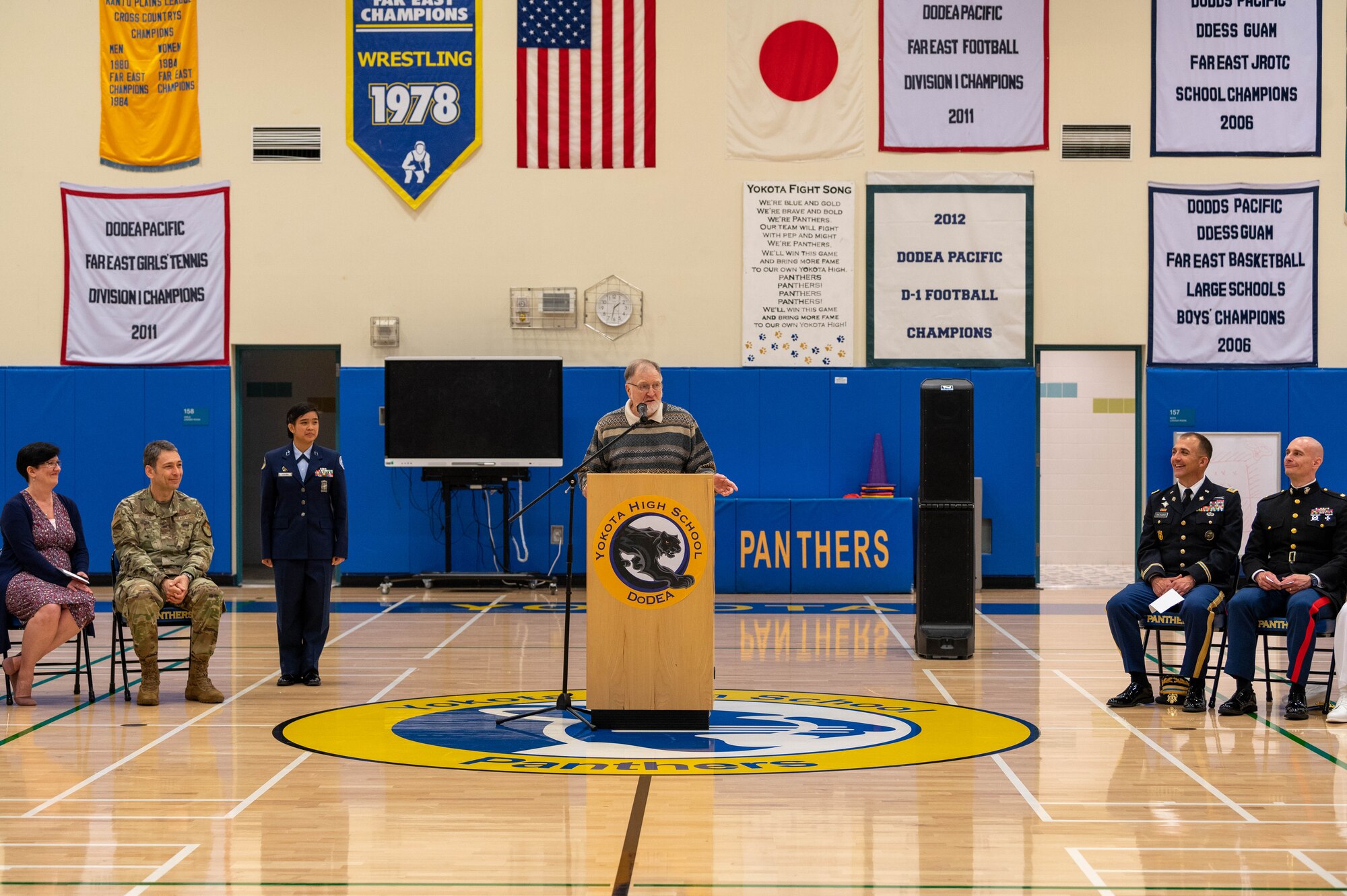 A high school teacher delivers a speech during a combat flag presentation ceremony.