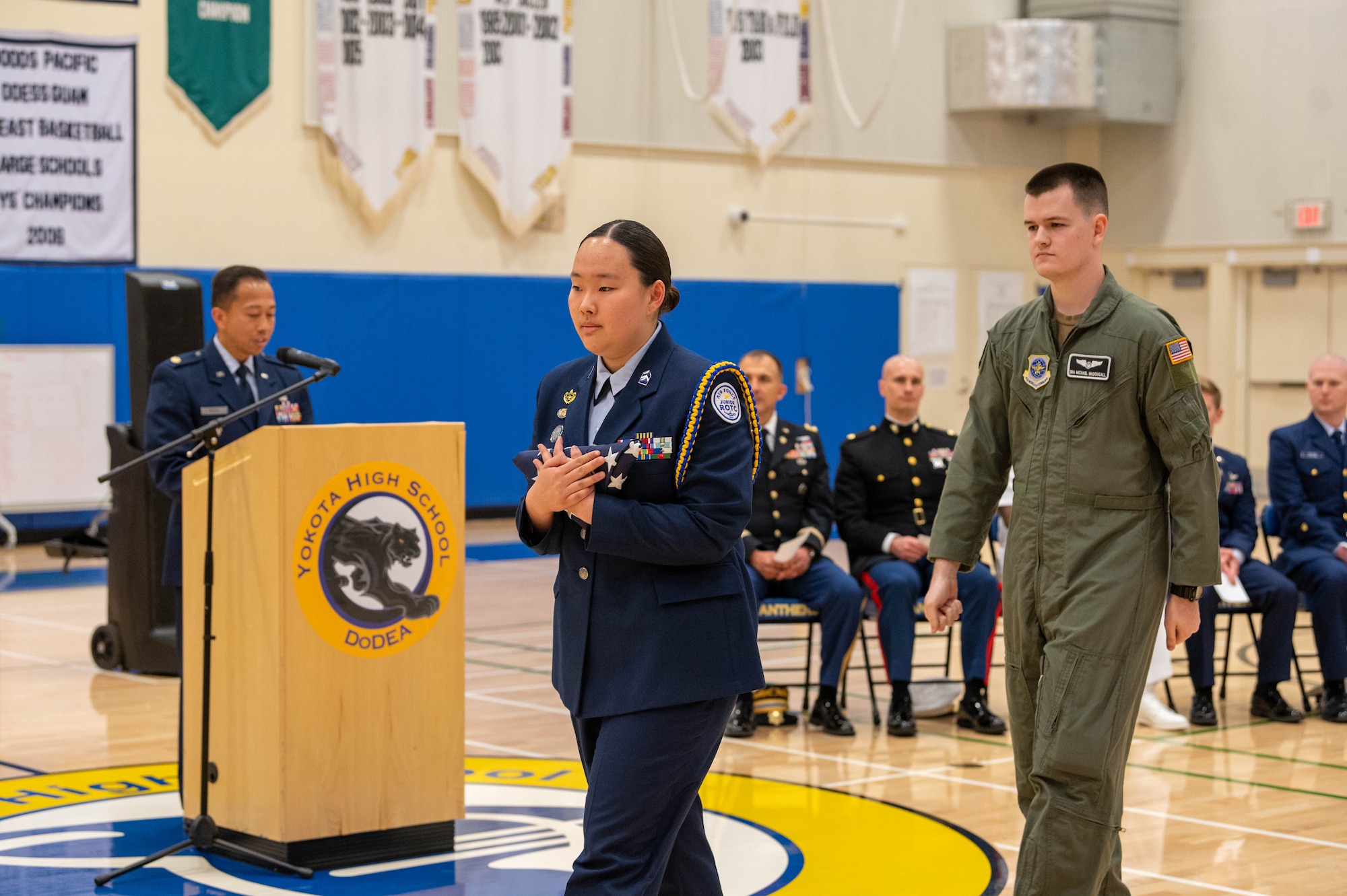 A high school student holds a combat flag that was presented to her by a military member during a ceremony.