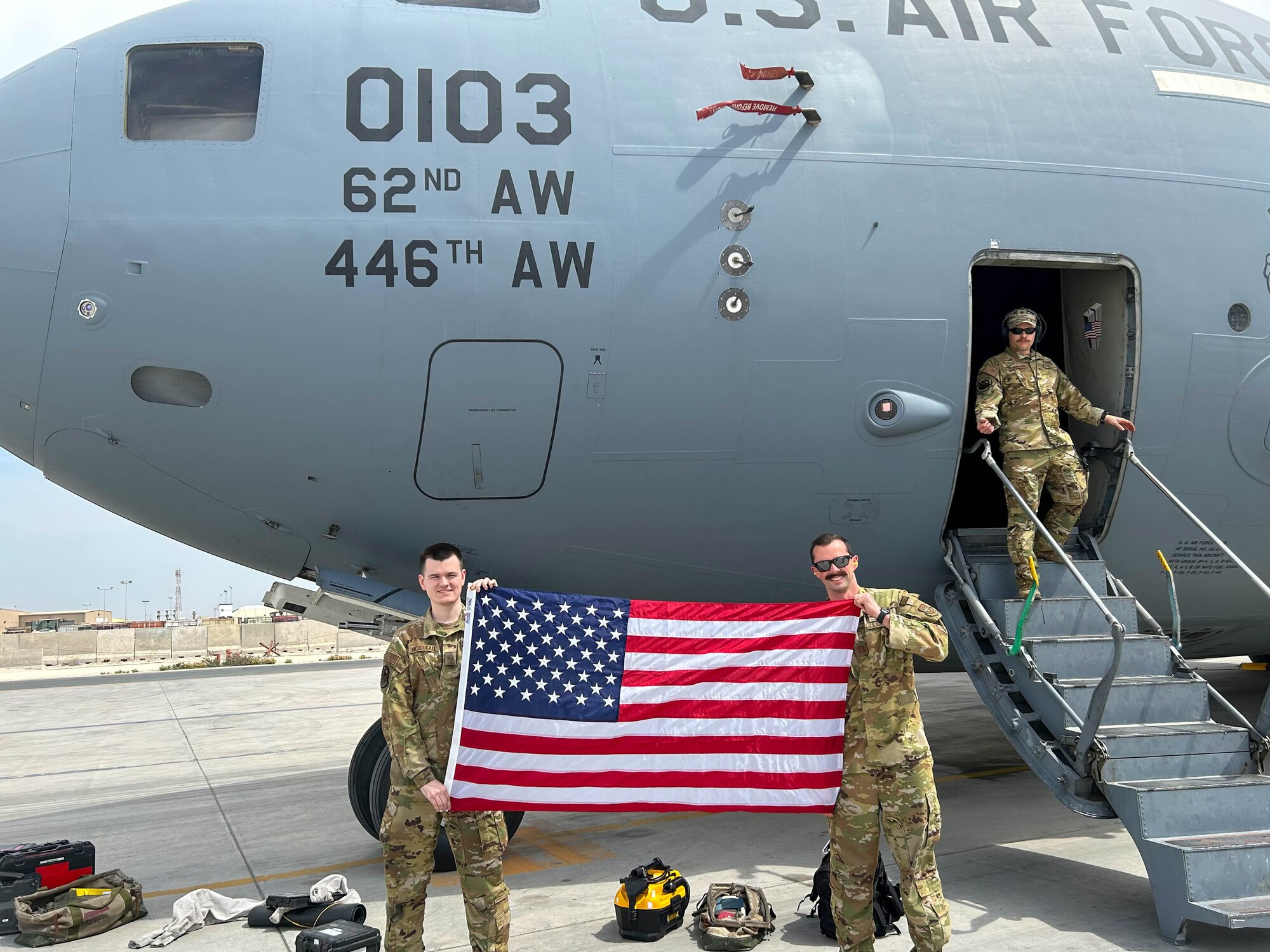 Two service members hold up an American flag.