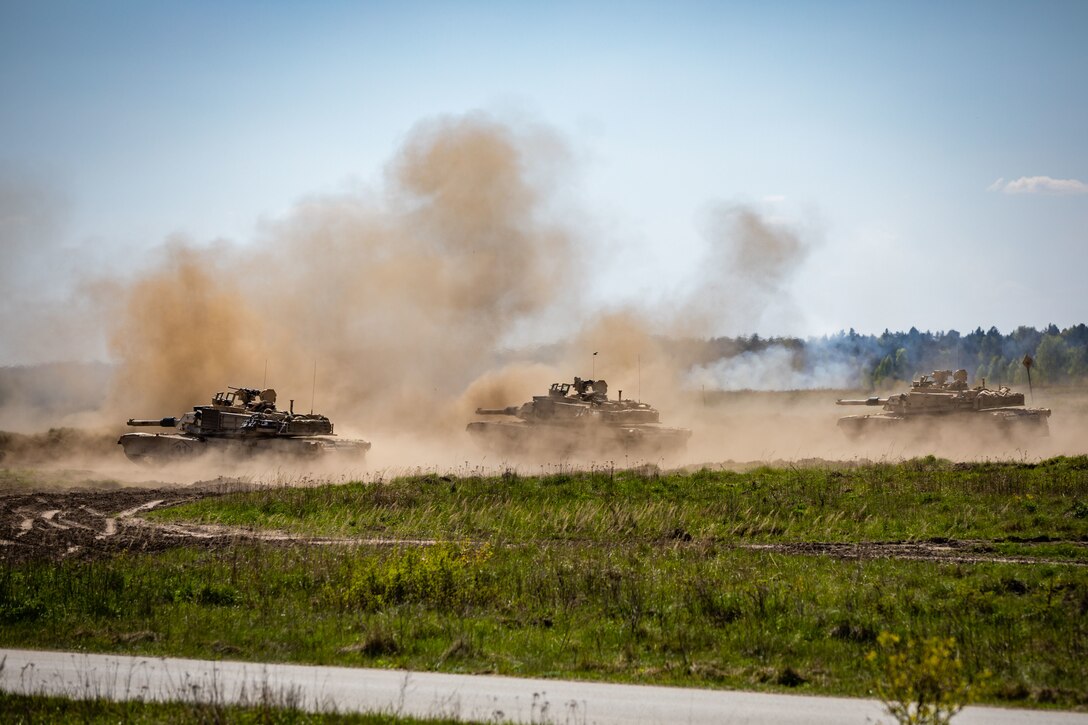 Soldiers in tanks fire at targets during a combined arms live fire exercise.