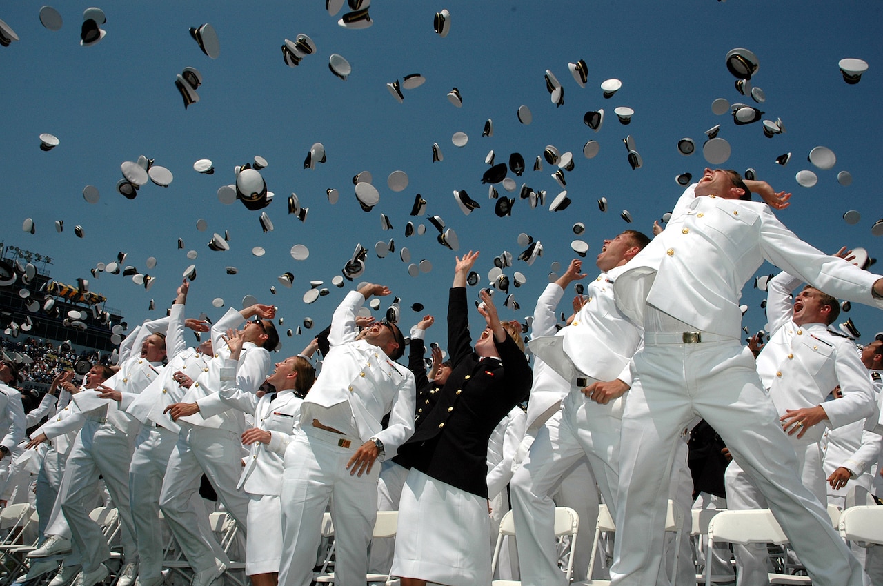 Naval Academy graduates toss their hats in celebration.