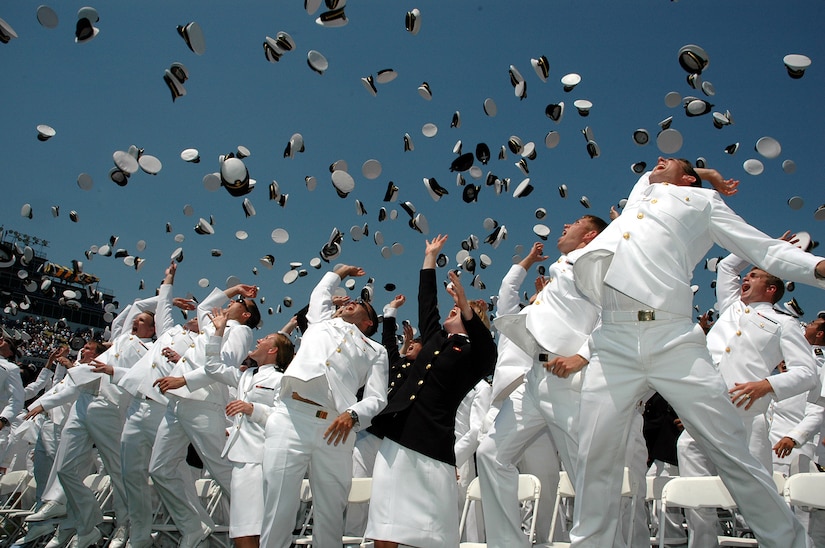 Naval Academy graduates toss their hats in celebration.