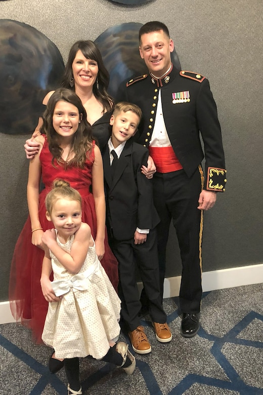 A uniformed Marine poses with family at a formal gathering.