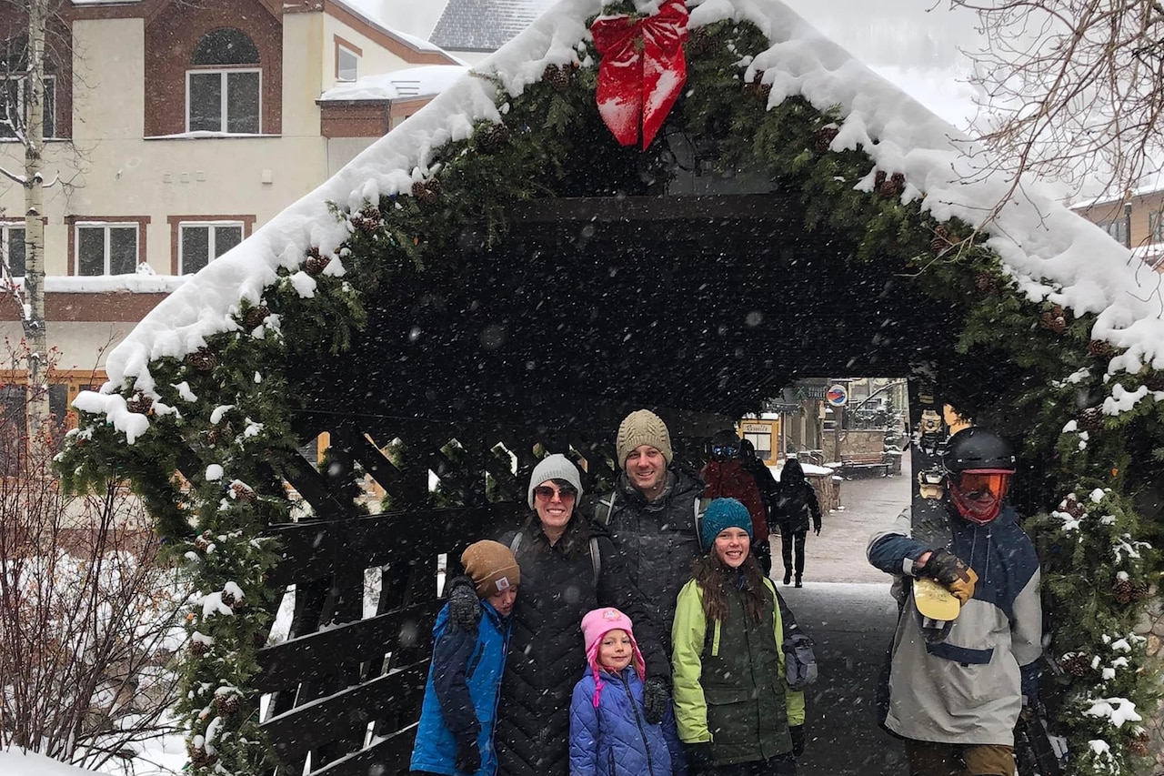 A family smiles while posing near Christmas decorations.