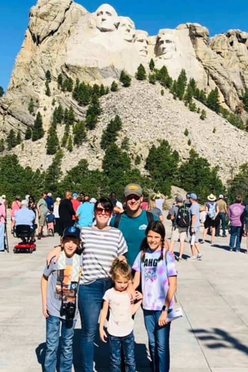 A family poses with Mount Rushmore in the background.