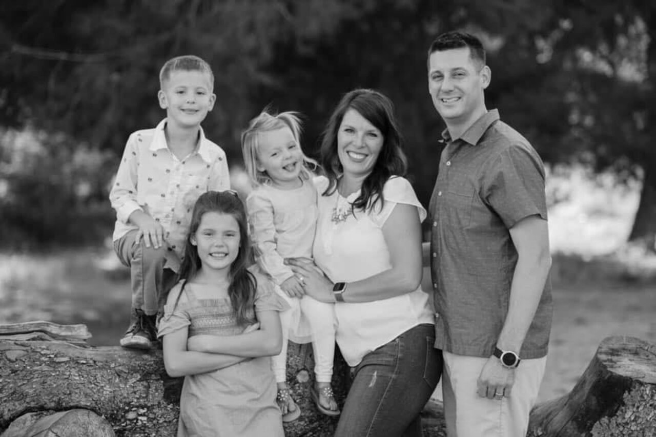 A family smiles in a black and white photo.