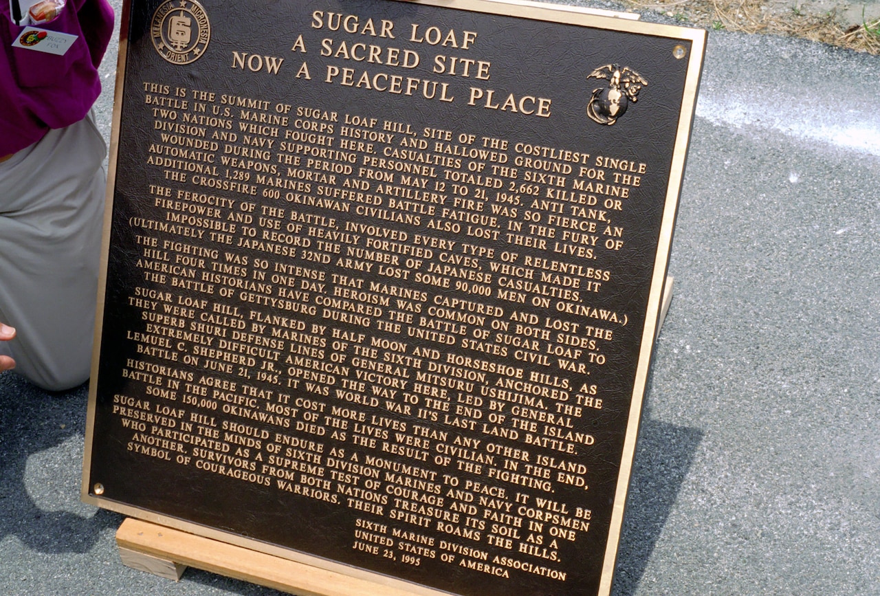 A bronze plaque discusses the battle that happened in Okinawa on Sugar Loaf Hill.
