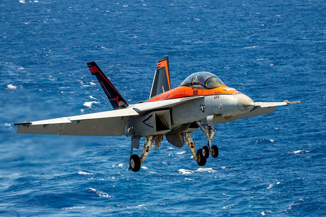 A military aircraft prepares to land on a Navy ship.