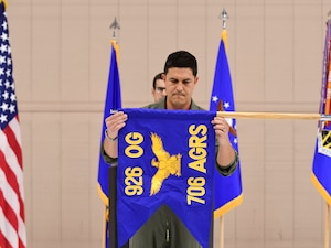 Lt. Col. Owen Birckett holds the blue guidon flag that reads "926 OG 706 AGRS" in bold, gold letters.