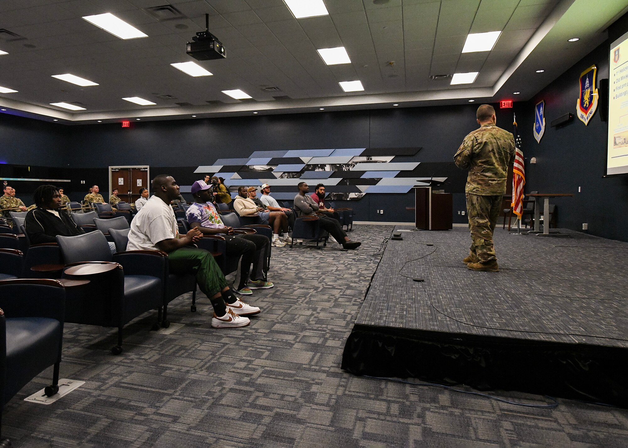 A crowd listens to a man speak on a stage.