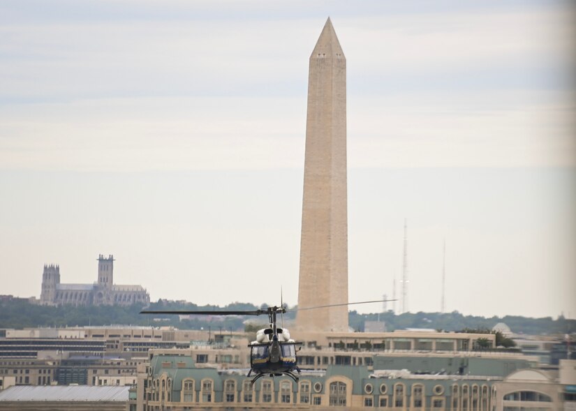 A helicopter flies towards the Washington Monument in Washington, D.C.