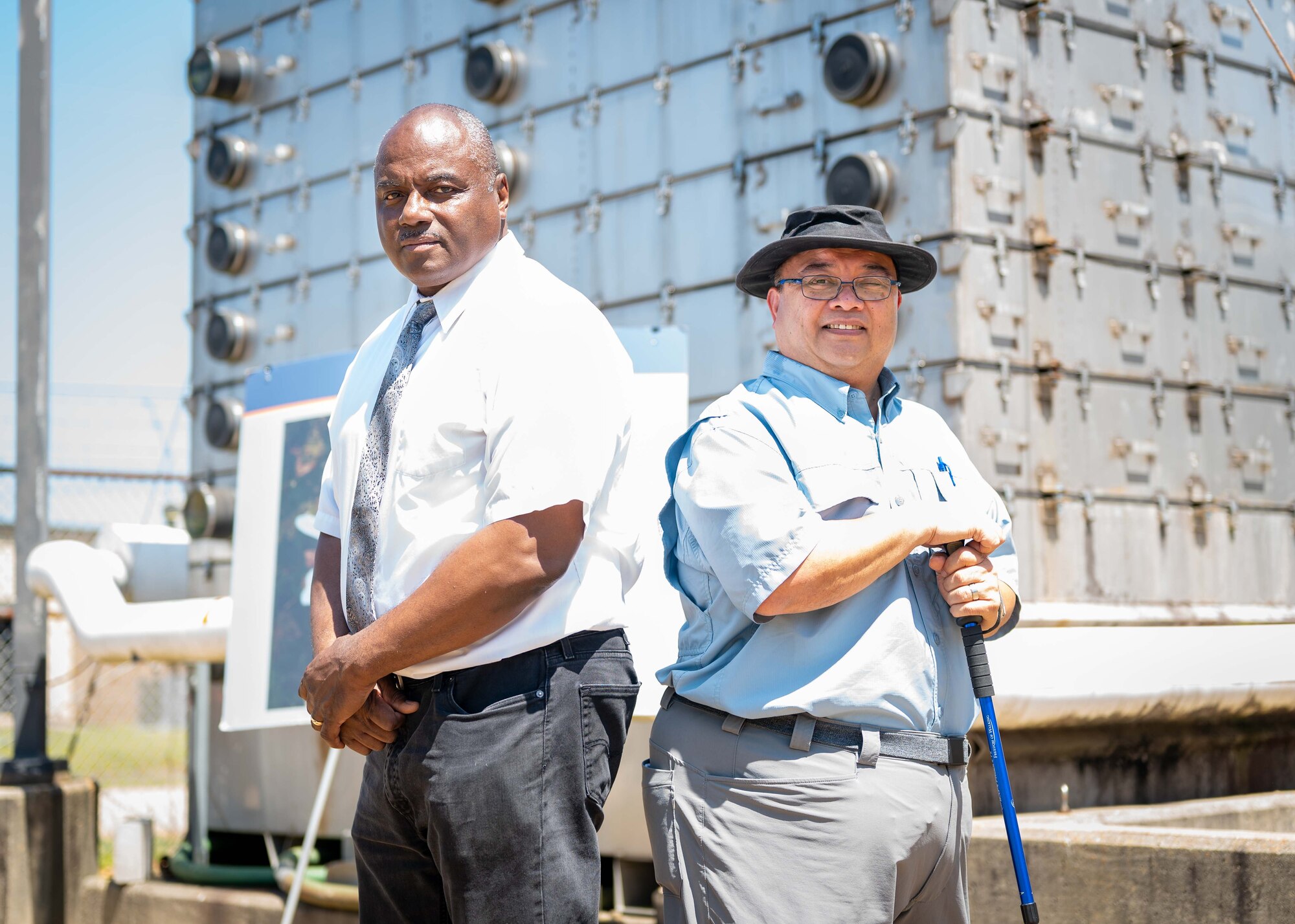 Wendell Williams (left) and Juvenal Salomon (right) pose for a photo in front of large groundwater treatment infrastructure.