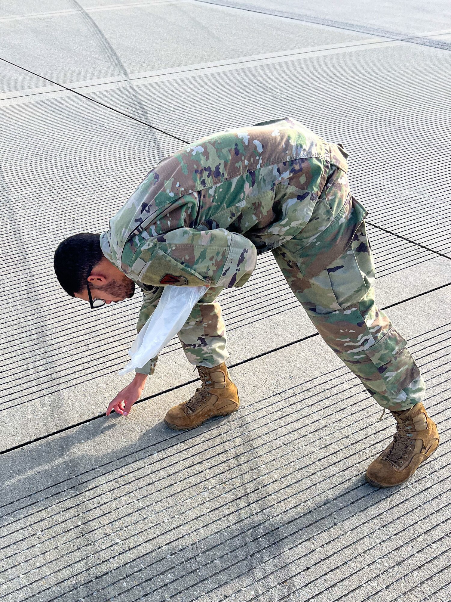 An Airman bends over to pick up debris.