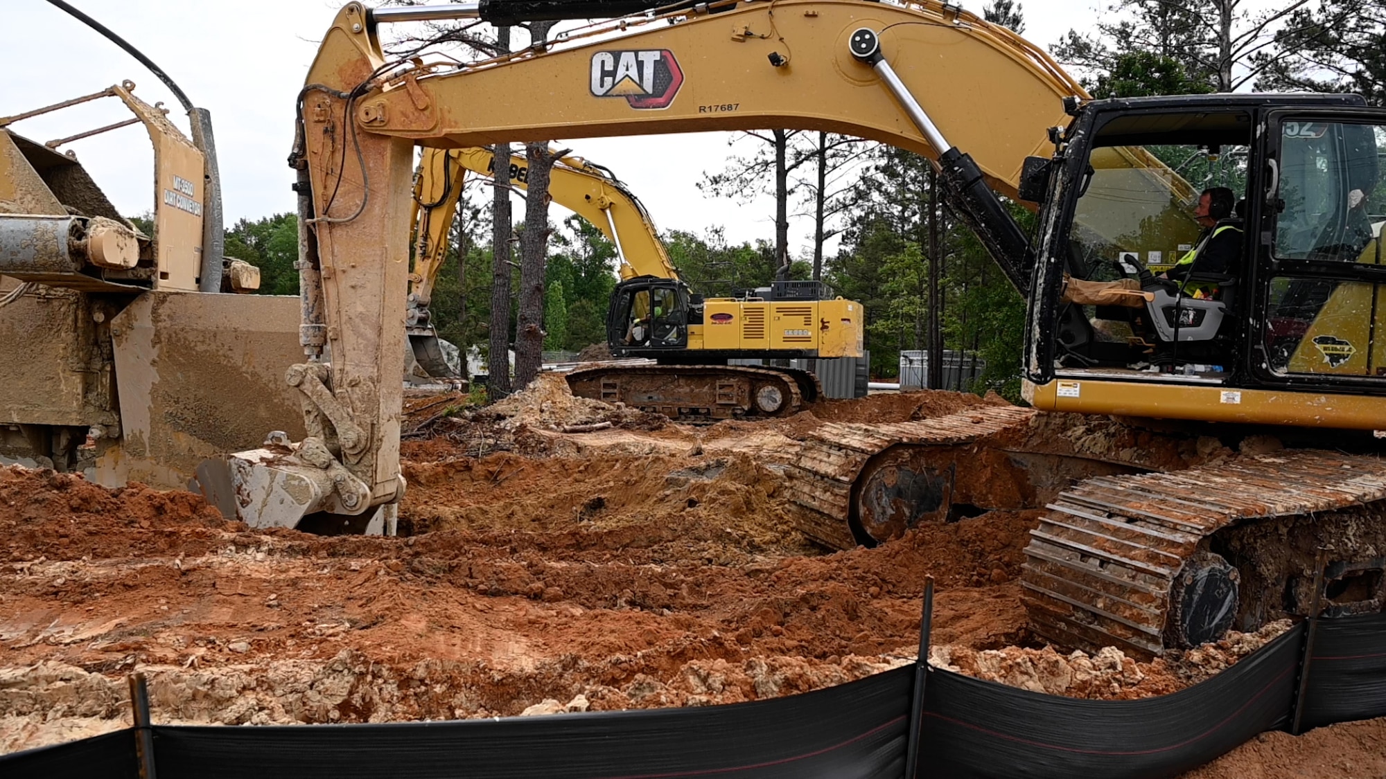 Construction workers use heavy machinery to build large trenches in the ground.