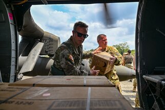 U.S. Army Col. Phillip Brown, Joint Task Force-Bravo commander, tosses boxes of Meals, Ready-to-Eat, to U.S. Army Maj. Levi Dillon, 1st Battalion, 228th Aviation Regiment operations officer, at a Servicio Nacional Aeronaval (SENAN) base.