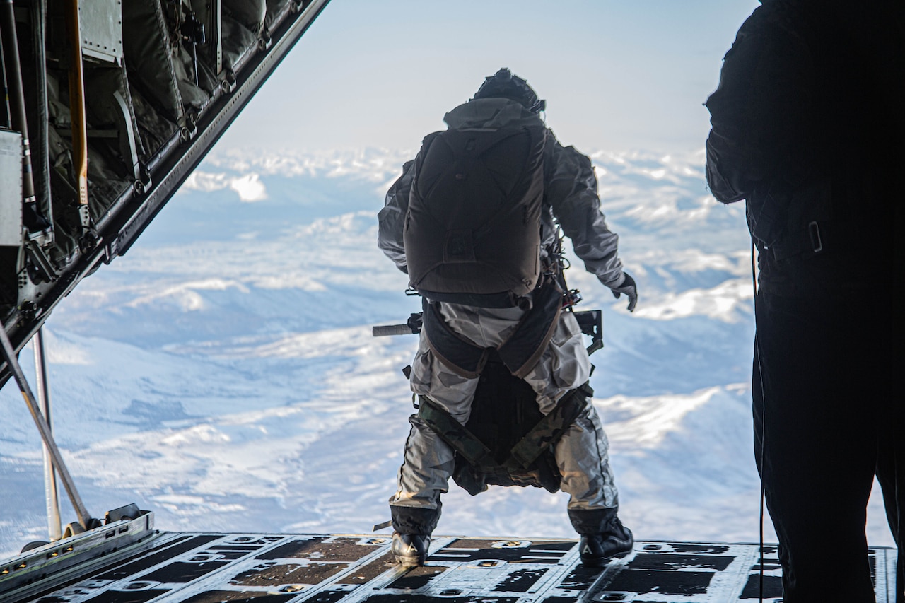 A paratrooper stands at rear or aircraft just before jumping out.