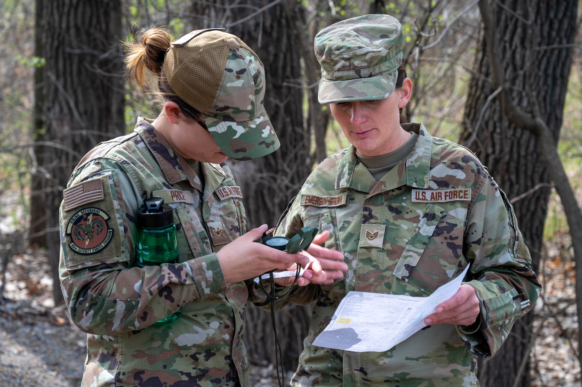 Staff Sgt. Alexandria Emerson-Brown, right, and Airman 1st Class Alina Price, both 934th Security Forces Squadron specialists, check their whereabouts using a compass and a map at Arden Hills, Minnesota, May 7, 2023. The 934 SFS conducted a routine land navigation course to refresh and brush up on the arduous process of using a compass and pace count. (U.S. Air Force photo by Senior Airman Matthew Reisdorf)
