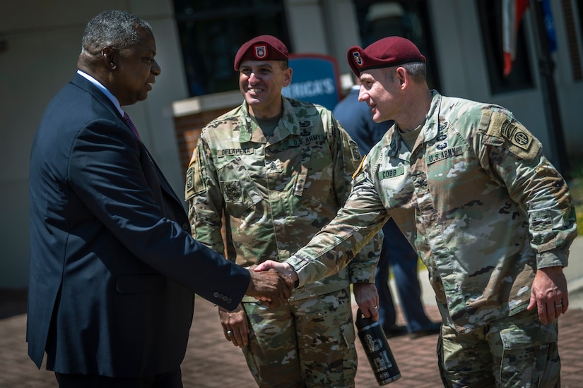 A man is greeted by two men in military uniform.