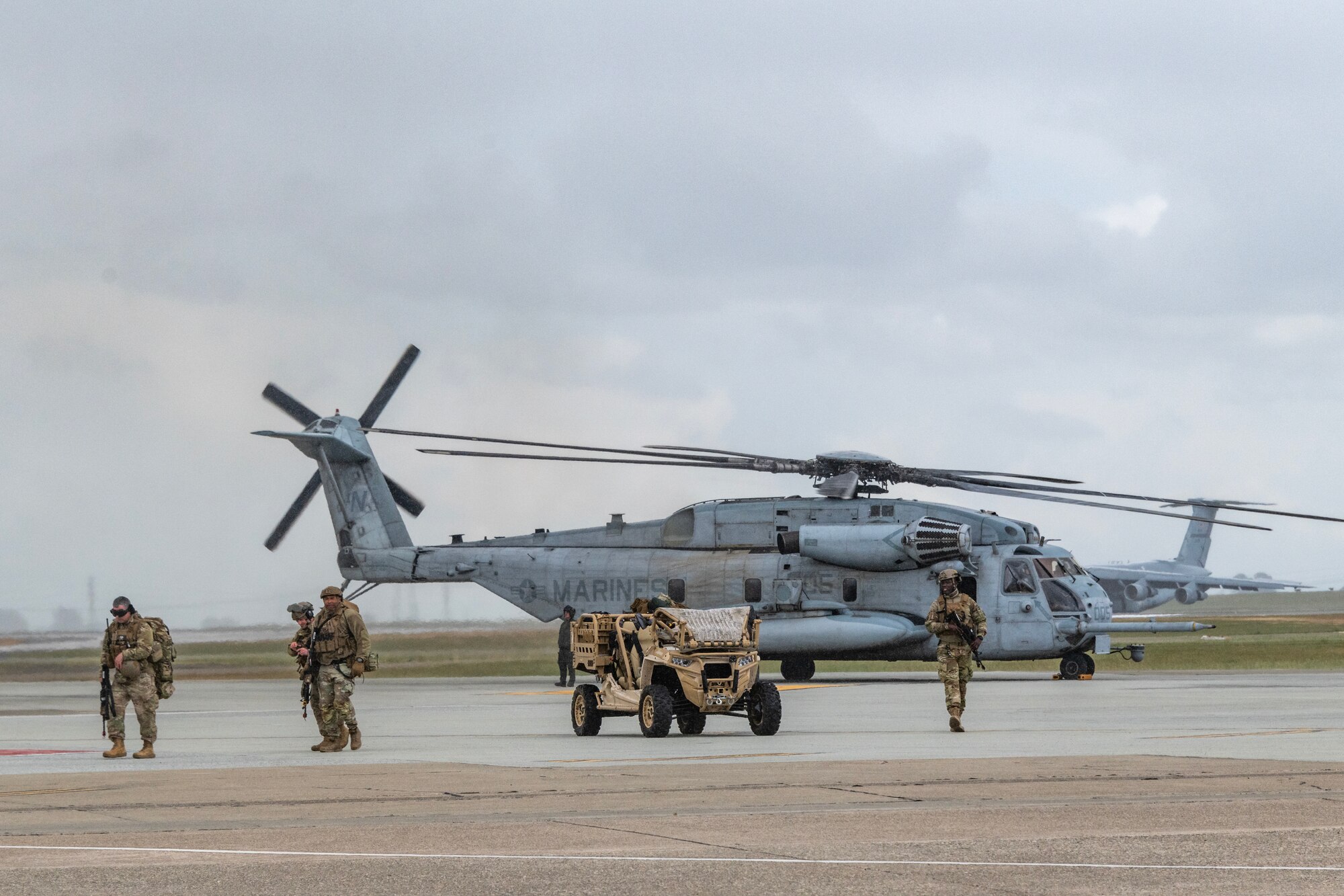 Airmen in front of a vehicle and a helicopter