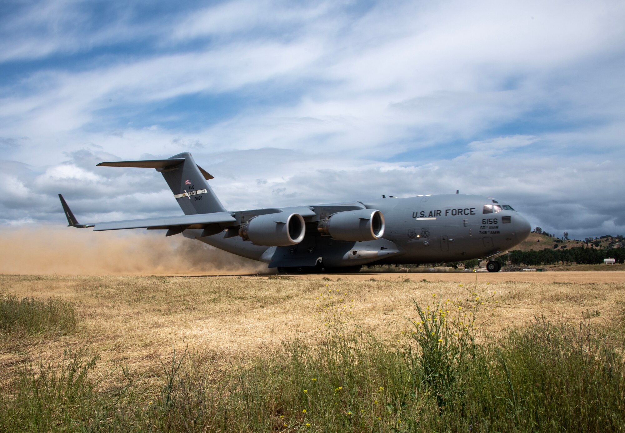 An aircraft takes off from a dirt runway