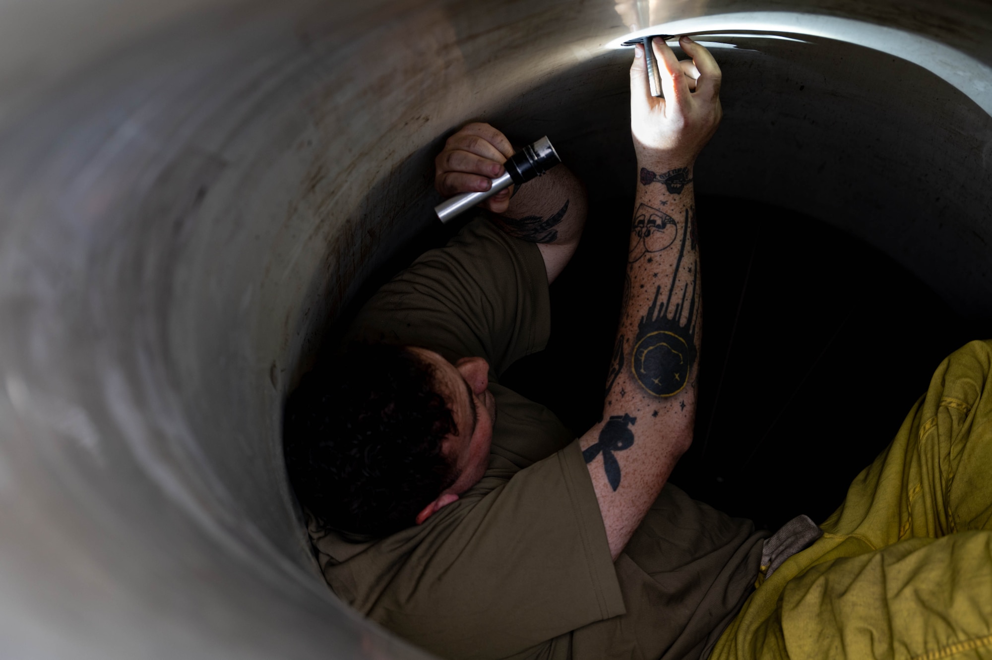 man in jet intake with flashlight