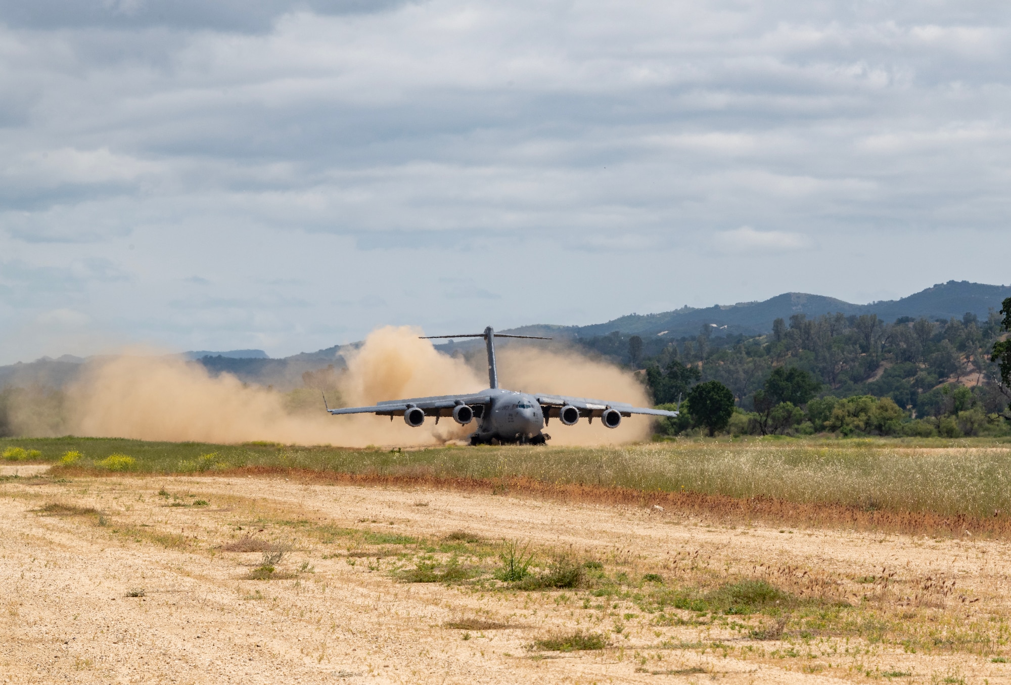 An aircraft lands on a dirt runway