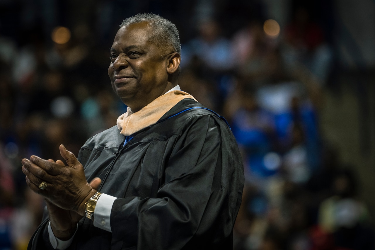 Secretary of Defense Lloyd J. Austin III claps his hands and smiles during  a speech.