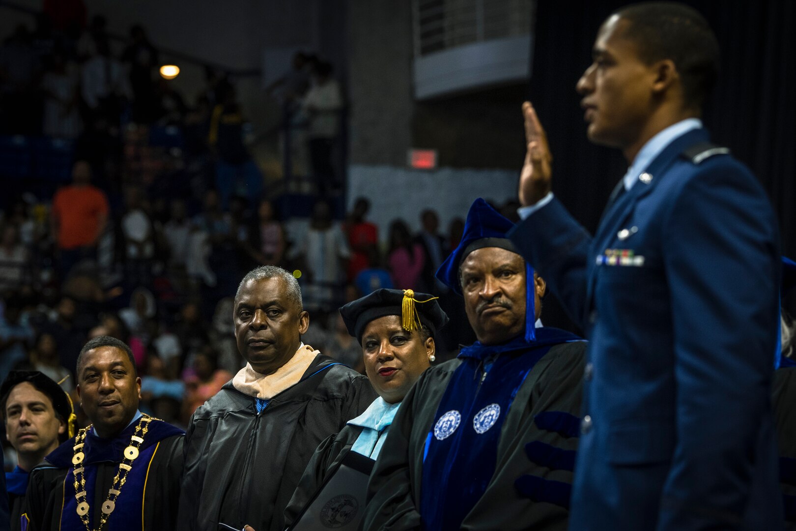 A cadet raises his right arm while other watch.