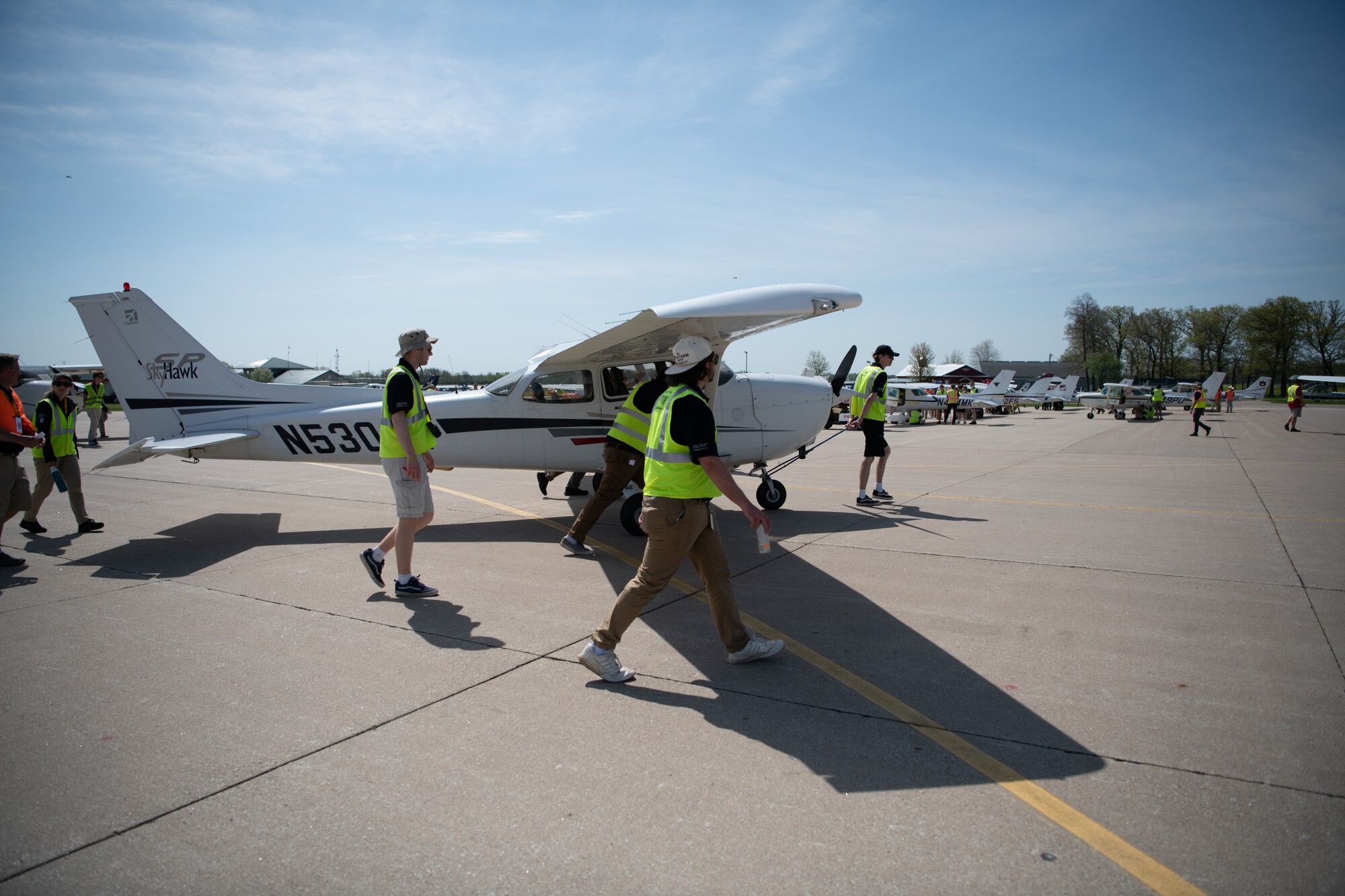 Collegiate aviation students tow an aircraft along a flight line