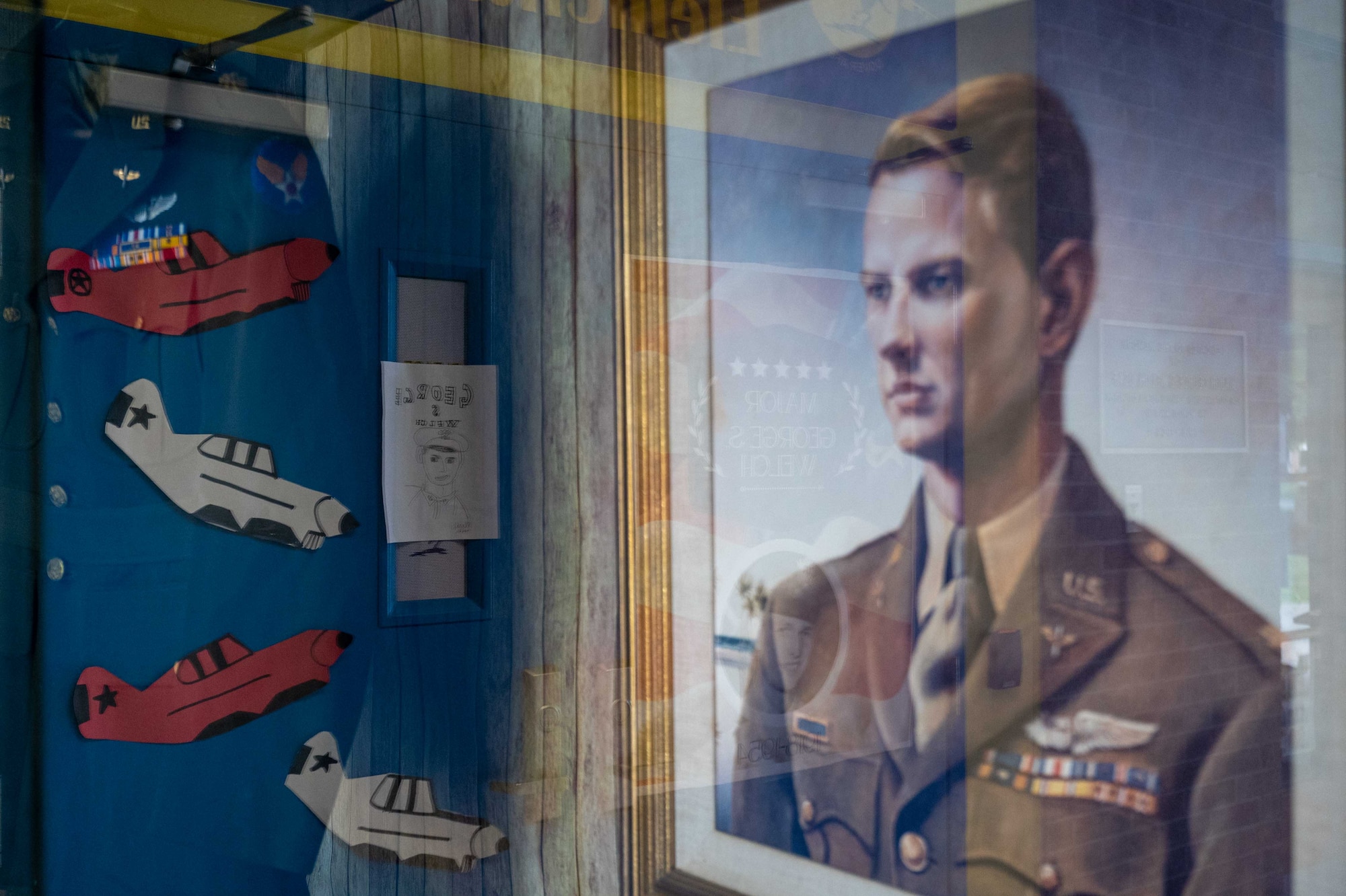 A student drawing and a photo of Maj. George S. Welch are displayed at Welch Elementary School on Dover Air Force Base, Delaware, May 12, 2023. Students, staff and community members came together for an assembly to celebrate the accomplishments and life journey of the Wilmington, Delaware native on his birthday, May 10. (U.S. Air Force photo by Staff Sgt. Faith Barron)