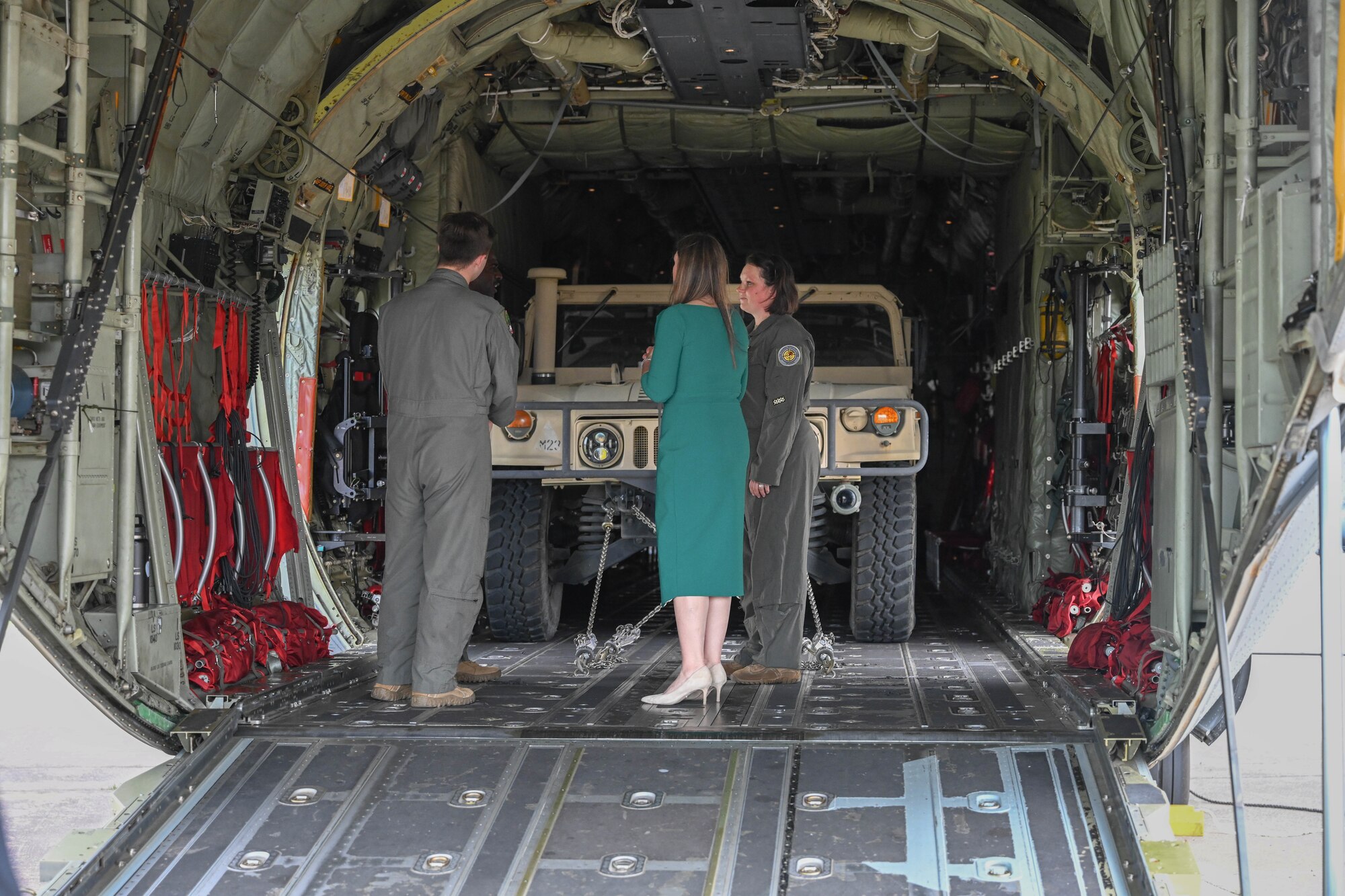 A man and woman in uniform speak with a woman on a plane.