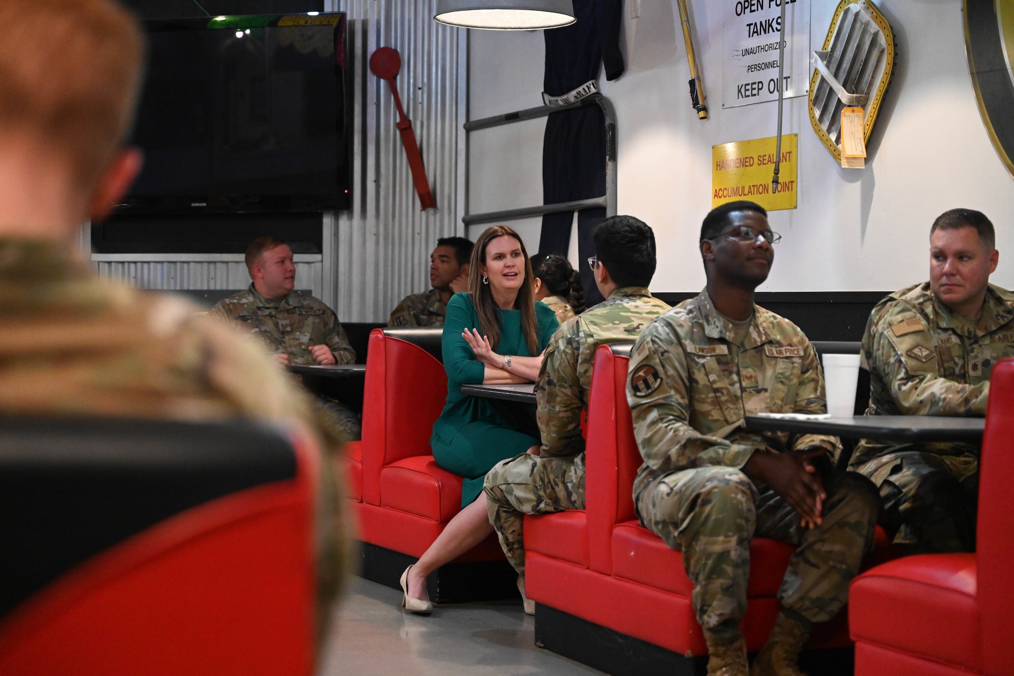 A woman sits at a table with people in uniform.