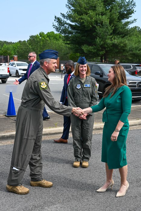 A man in uniform shakes a woman's hand.