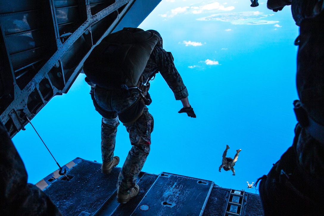 A Marine prepares to jump out of a helicopter .