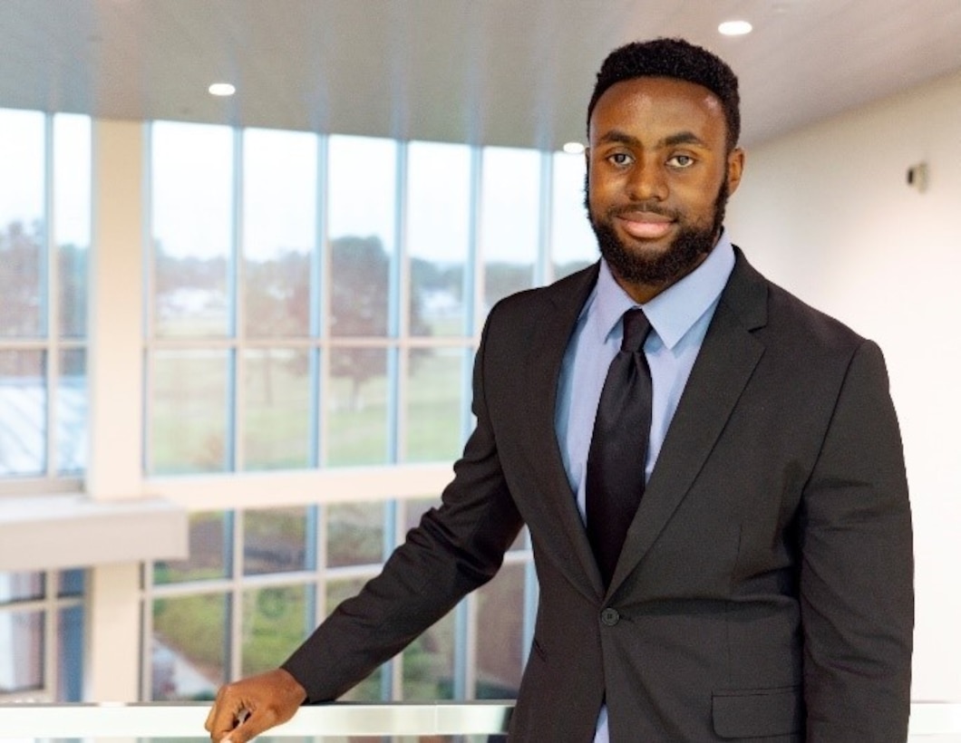 A smiling Black man against a railing in an office building