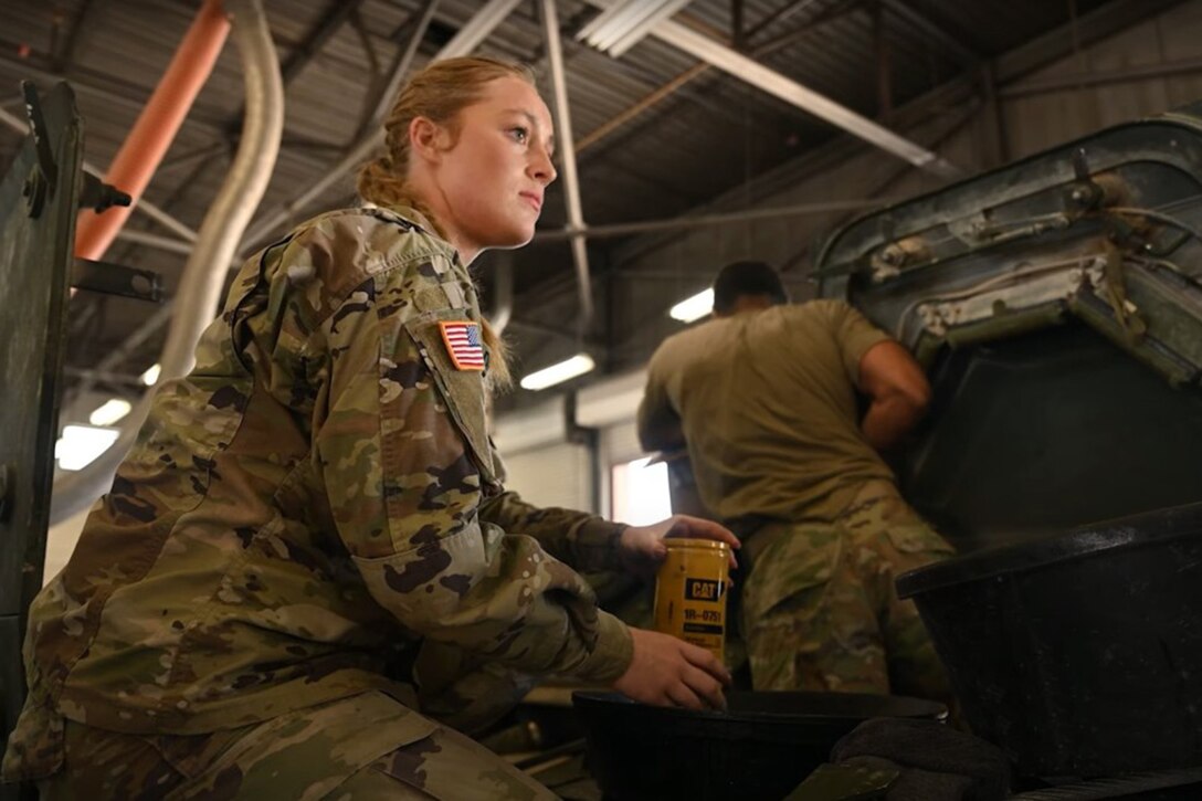 A soldier looks in the distance while seated in a garage.