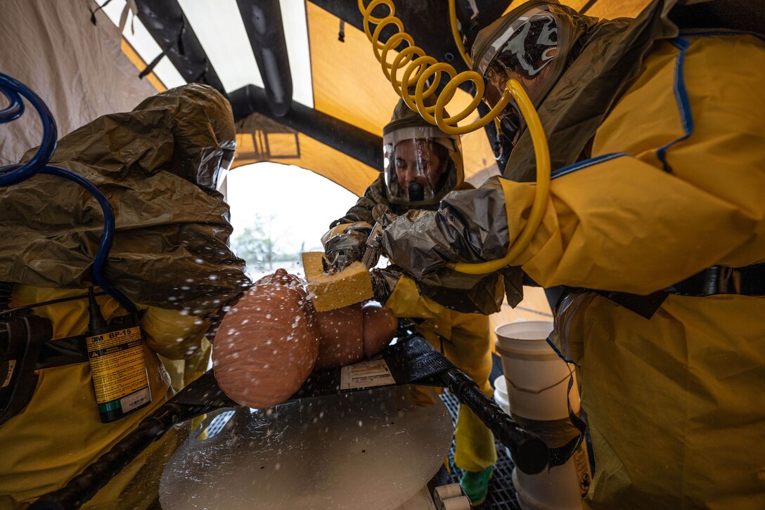 Airmen wash a training mannequin.
