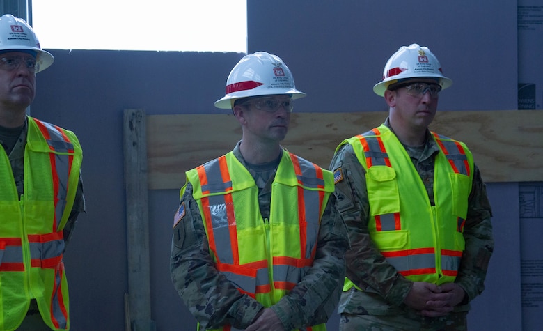 People stand in hard hats and vests.