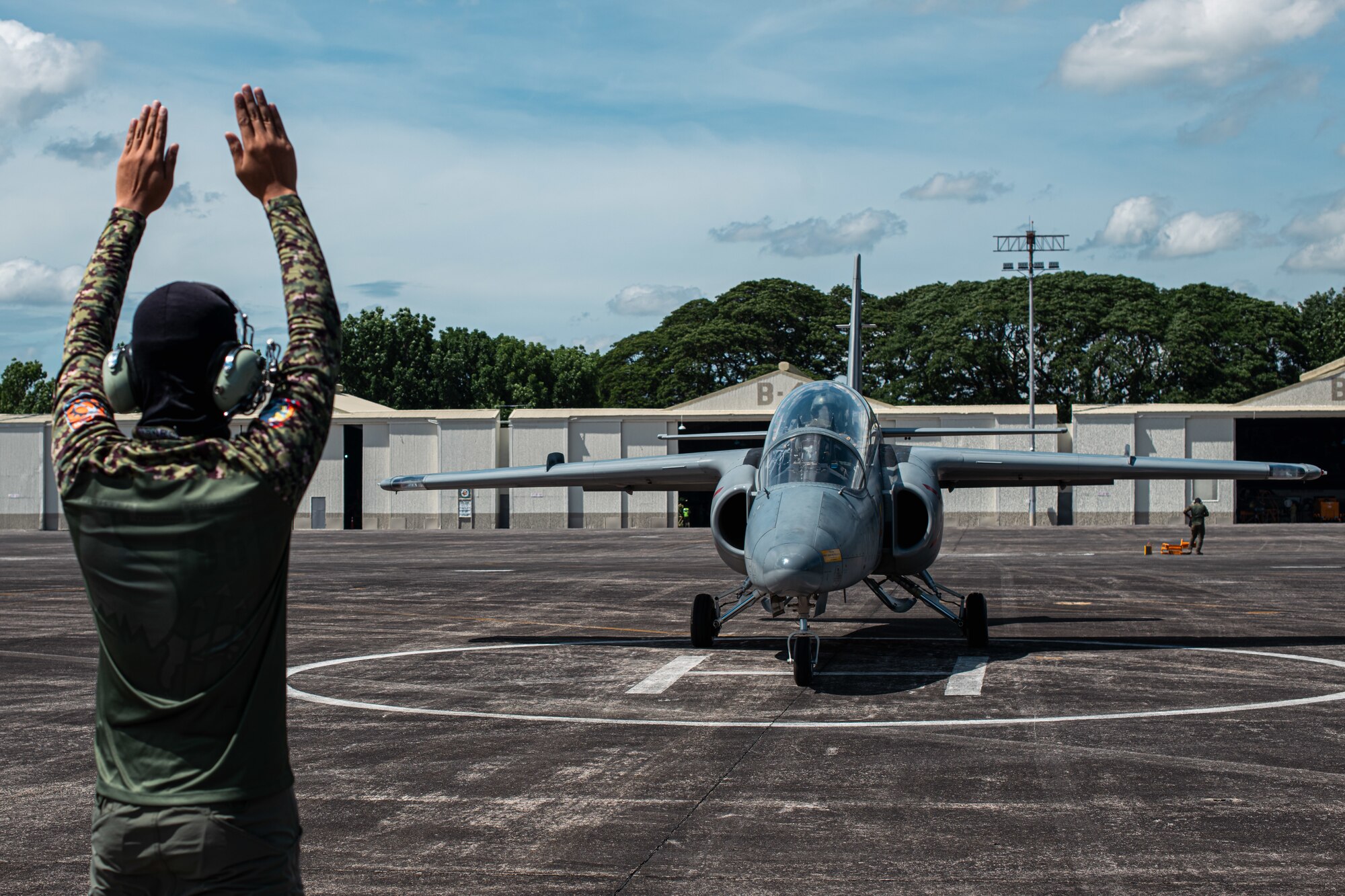 a photo of a Philippine Air Force member marshaling a FA-50PH