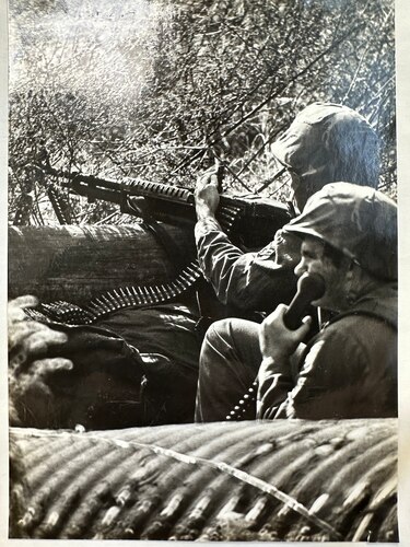 An M-60 machine gunner mans a defensive fighting position during air base ground defense training in April 1983.  His wingman is using a field telephone to communicate with the defense sector command post.  Lt. Col. Charles R. Piver, 375th Security Police Squadron commander, would implement a rigorous combat training program that would be put to real-world use within six months of this event. (Courtesy Photo)