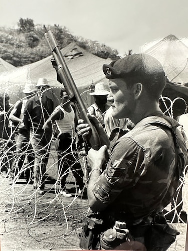 A Security Policeman stands guard over Grenadian and Cuban prisoners during Operation URGENT FURY in late 1983.  The major command insignia worn on the beret pre-1997 is a prior version of the current beret which is when the “Defensor Fortis” cloth flash was adopted.  The Military Airlift Command insignia on this SP denotes that he was deployed from a MAC base. (375th Air Mobility Wing Historical Archives)