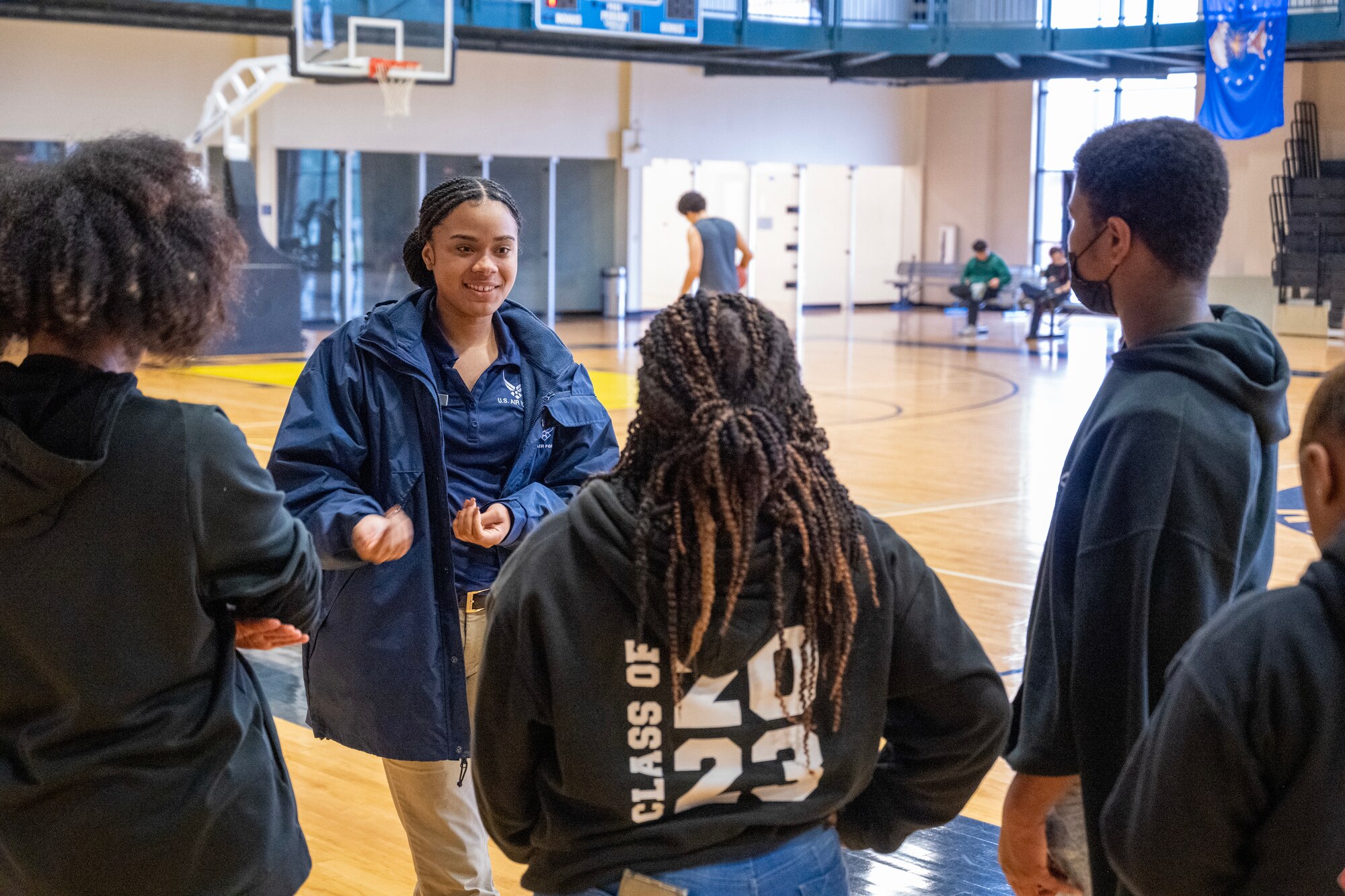 A group of people conversate in a gymnasium.