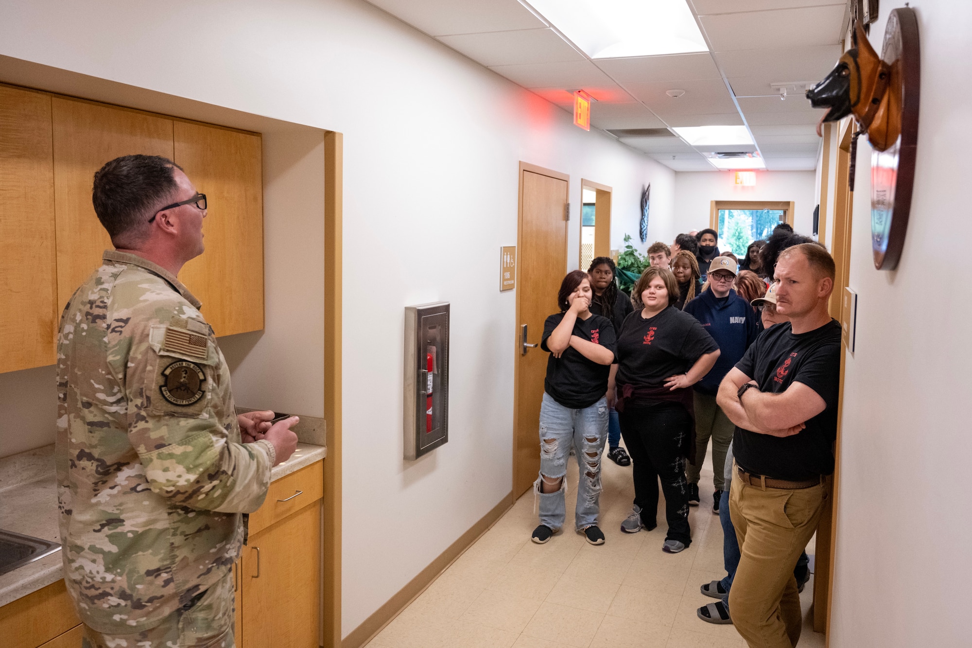 A man in uniform speaks to young men and women.