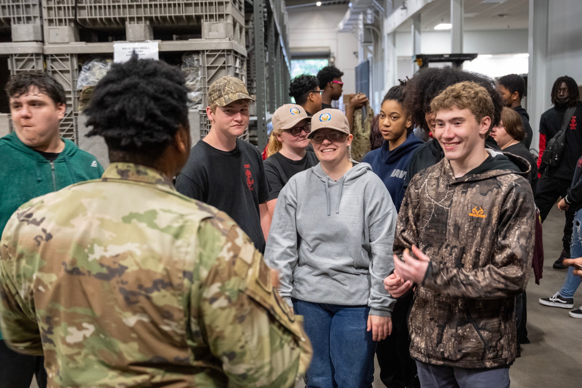 A man in uniform speaks to a group of young men.