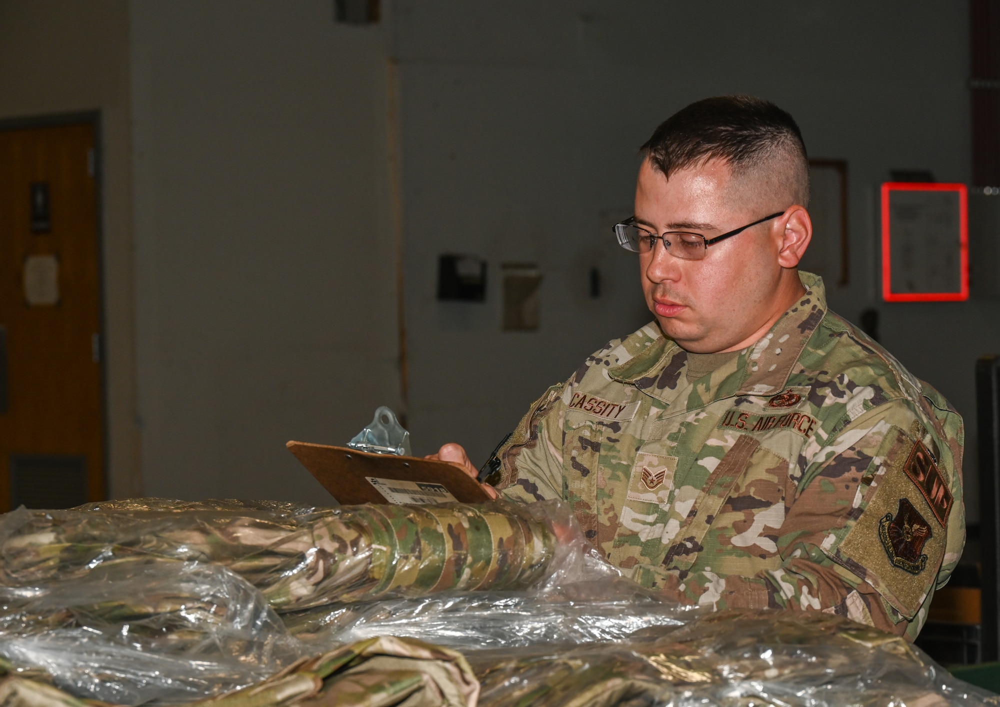 U.S. Air Force Staff Sgt. Eric Cassity, 509th Logistics Readiness Squadron, Individual Protective Equipment supervisor, goes through the list of service members who require a deployment kit at Whiteman Air Force Base, Missouri, May 9, 2023. To personalize the deployment kits, IPE had to reach out to all the units with members who require a kit and collect their names and sizes. (U.S. Air Force photo by Airman 1st Class Hailey Farrell)