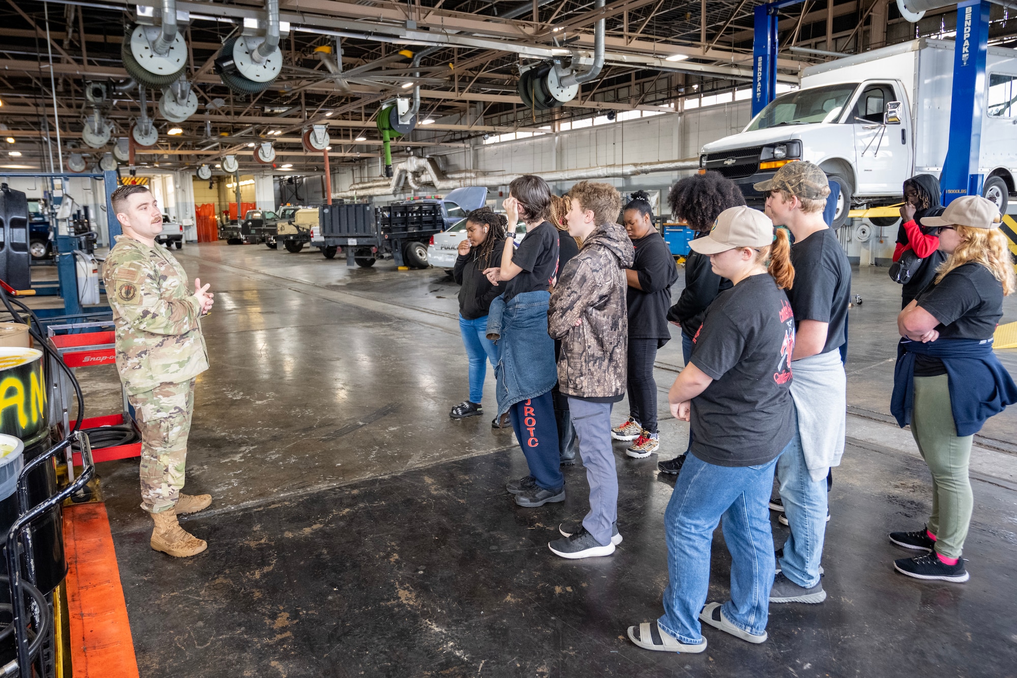 A man in uniform speaks to young men and women.